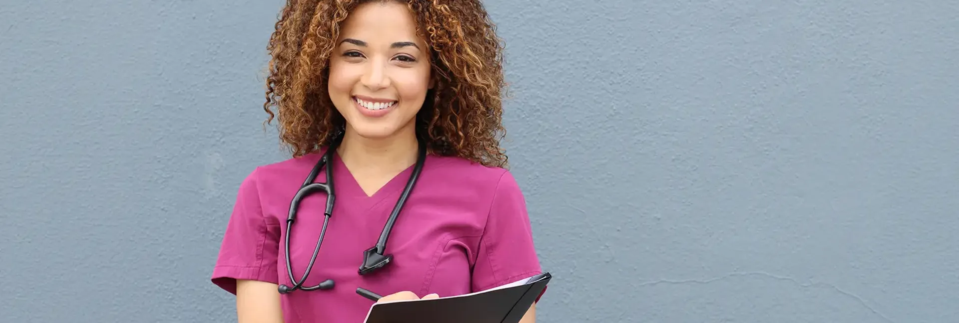 Black woman smiling with a stethoscope and folder