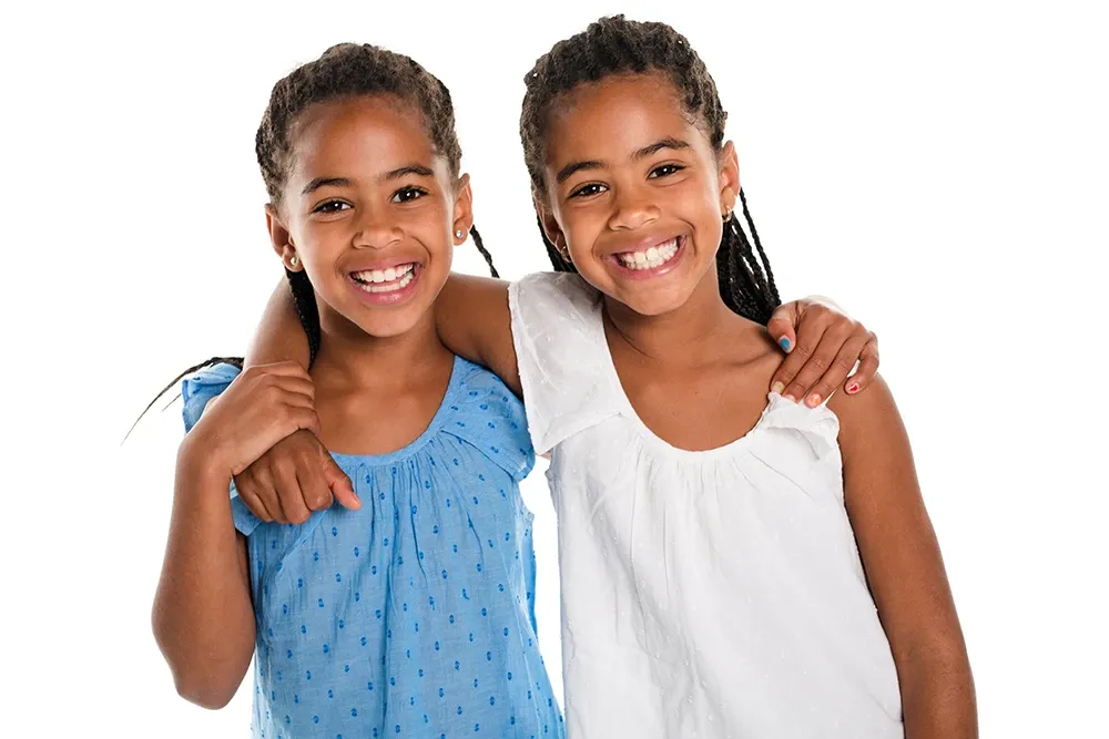 Two sisters, arm-in-arm, big smiles