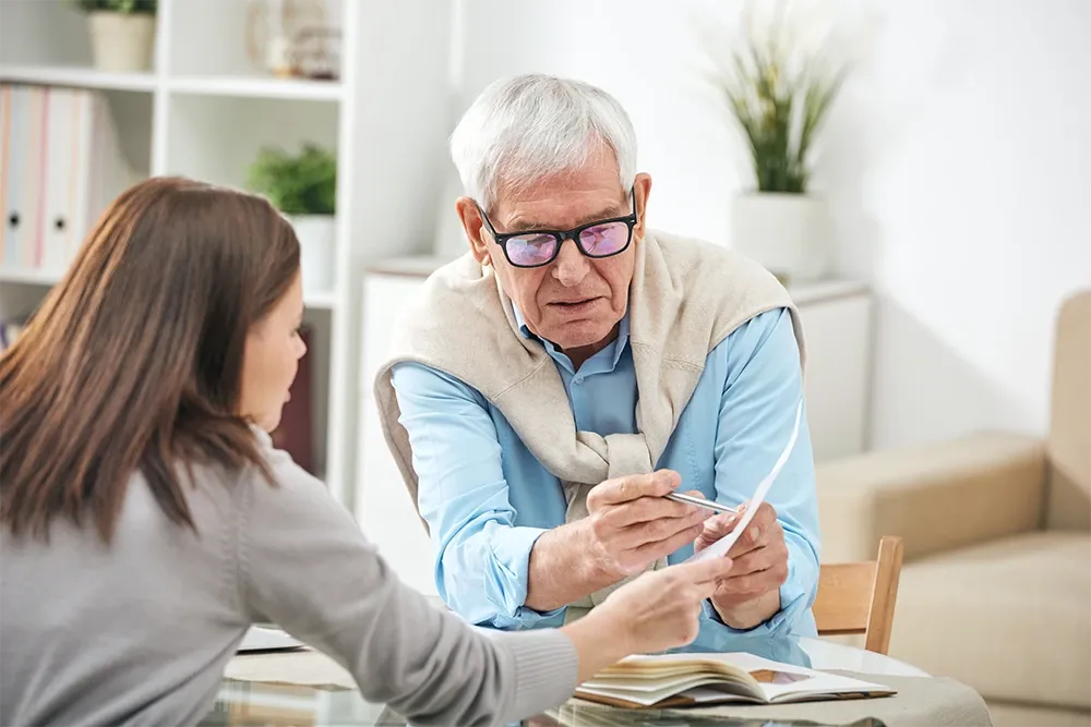 Older man and younger woman discussing paperwork
