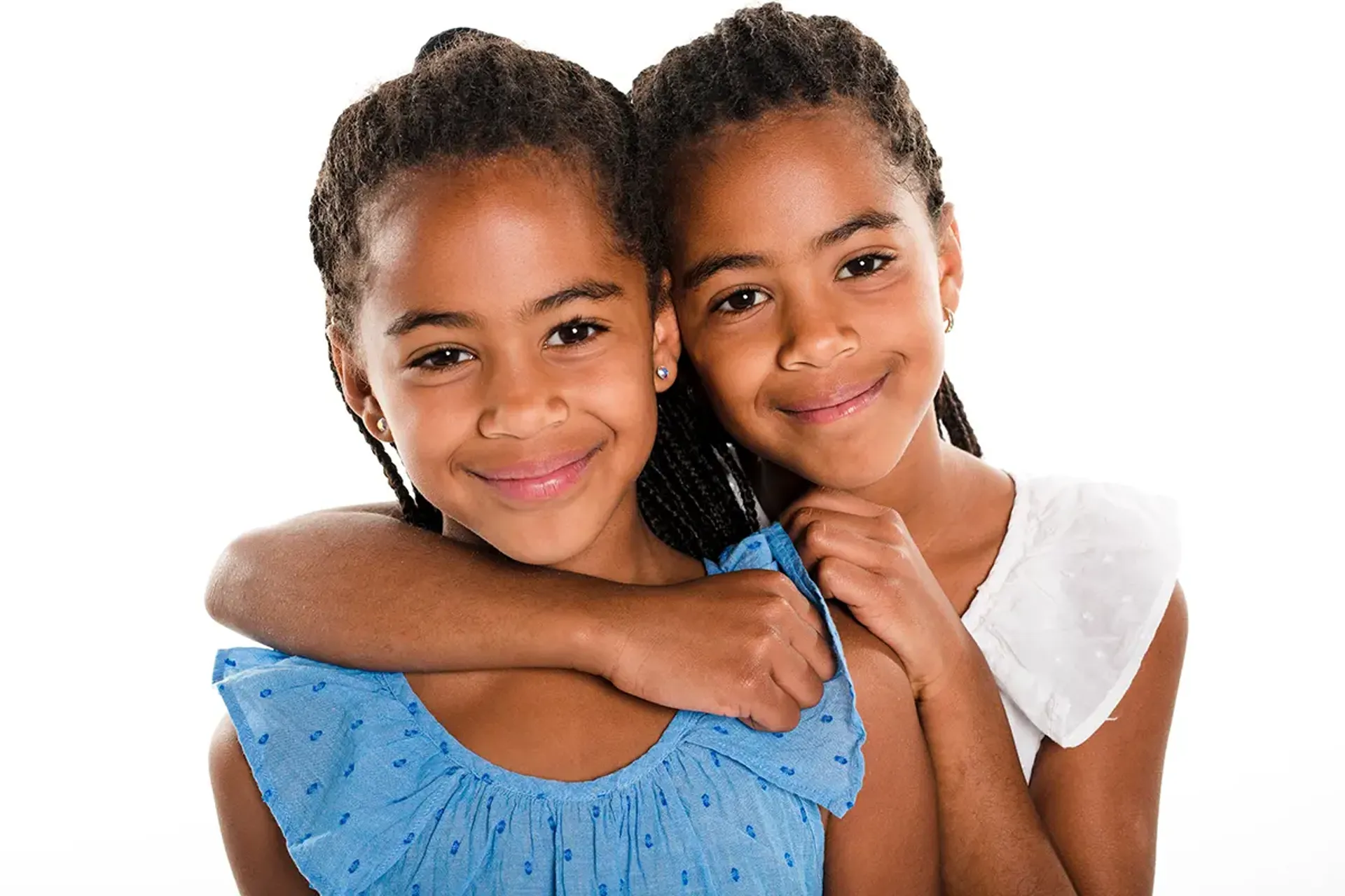 Two young sisters, arm-in-arm, posing for photo