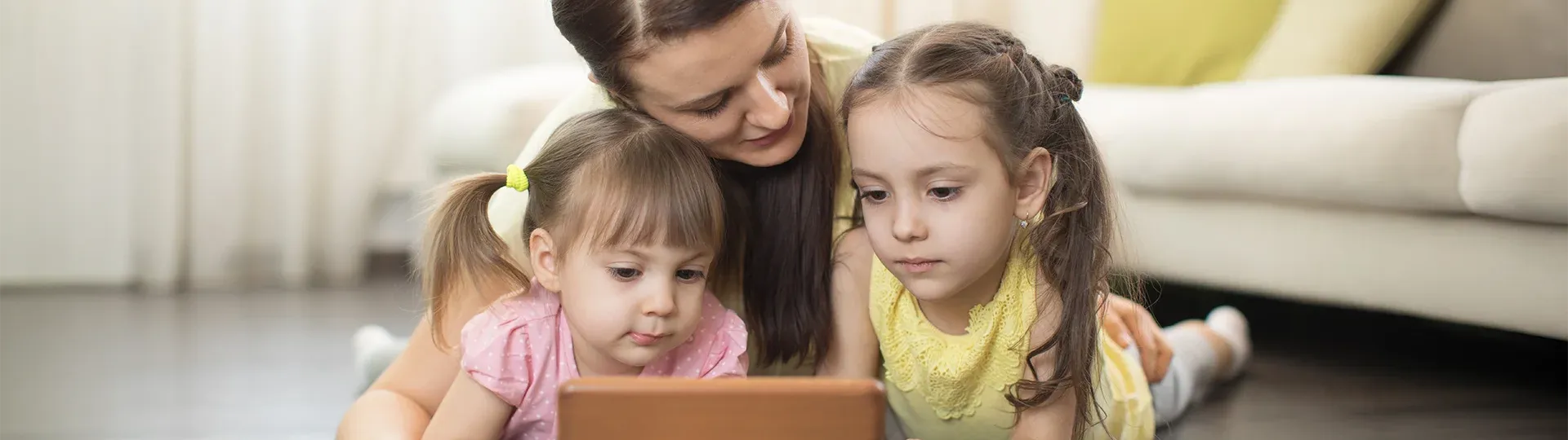 Mother with children use iPad lying on floor in living room