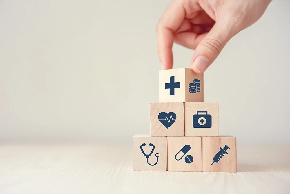 A hand stacking blocks with health-related icons on each