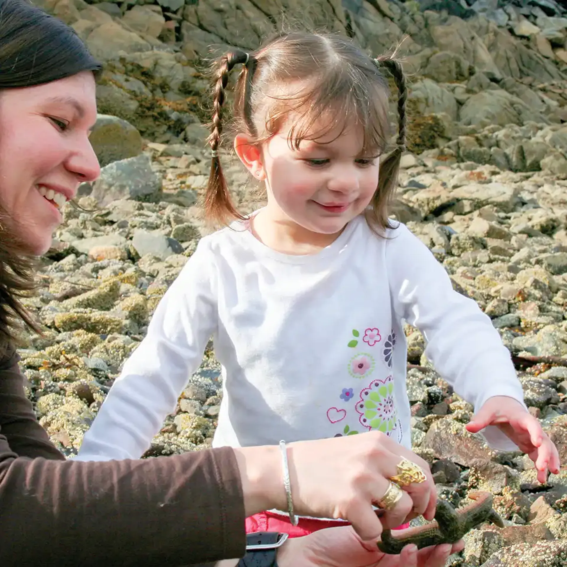 Carol: Mom showing daughter a starfish on a rocky beach