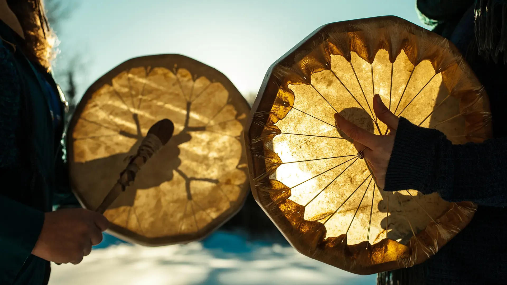 Women holding and playing their sacred drums outdoors in the wintertime 