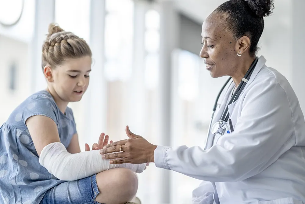 Back doctor examining girl with broken arm