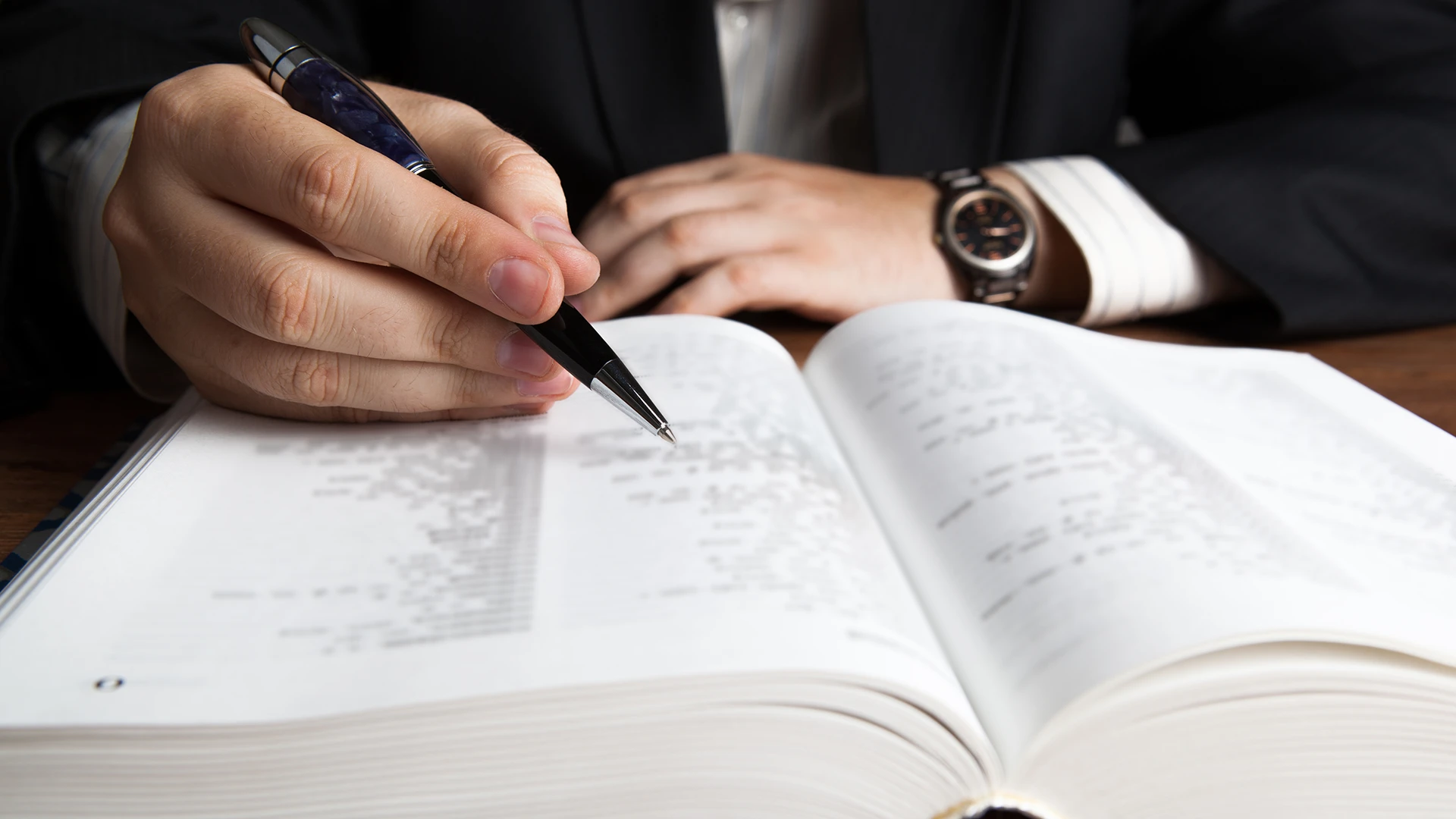 Man with pen looking up word in a book