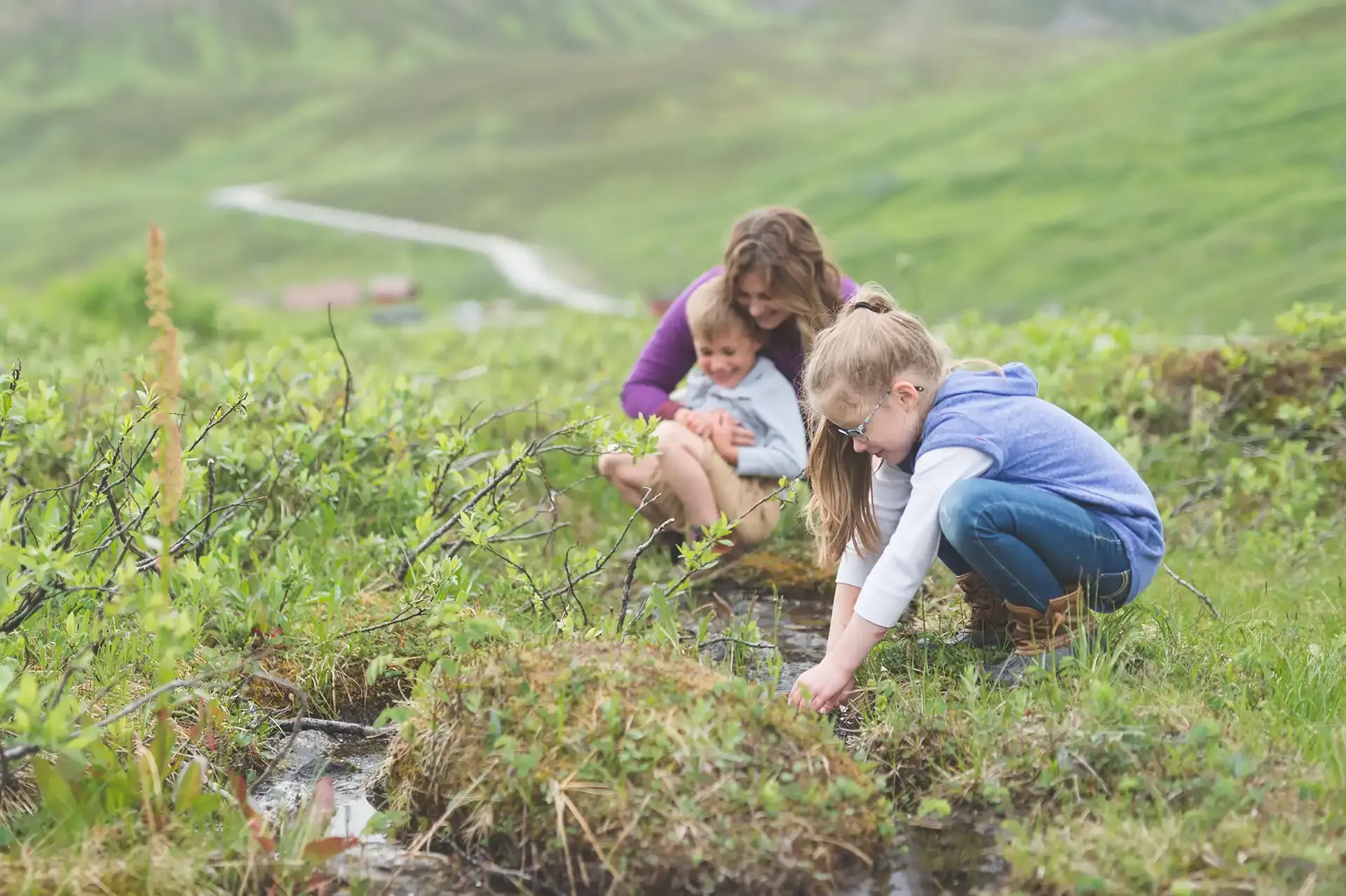Mom helping kids wash their hands in a small creek
