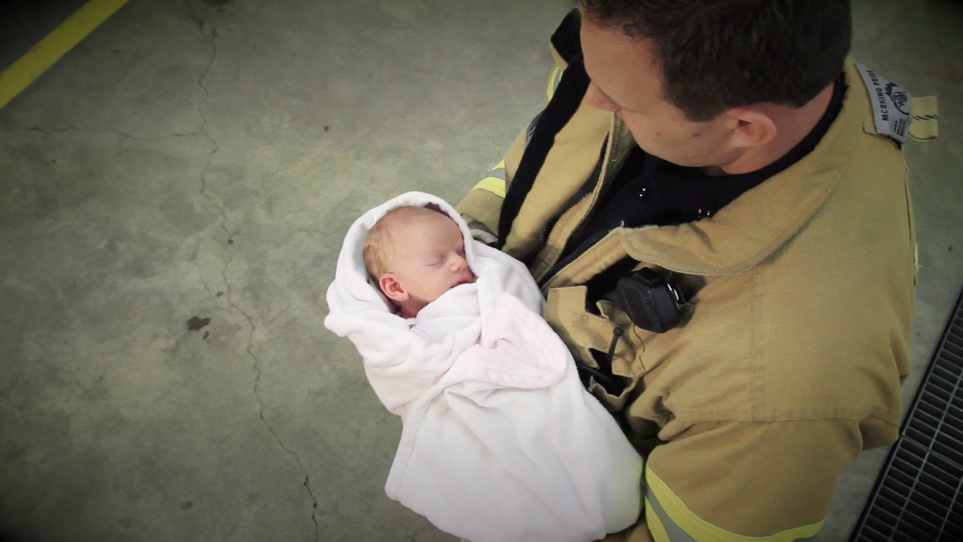 Looking down on a fireman holding a swaddled baby