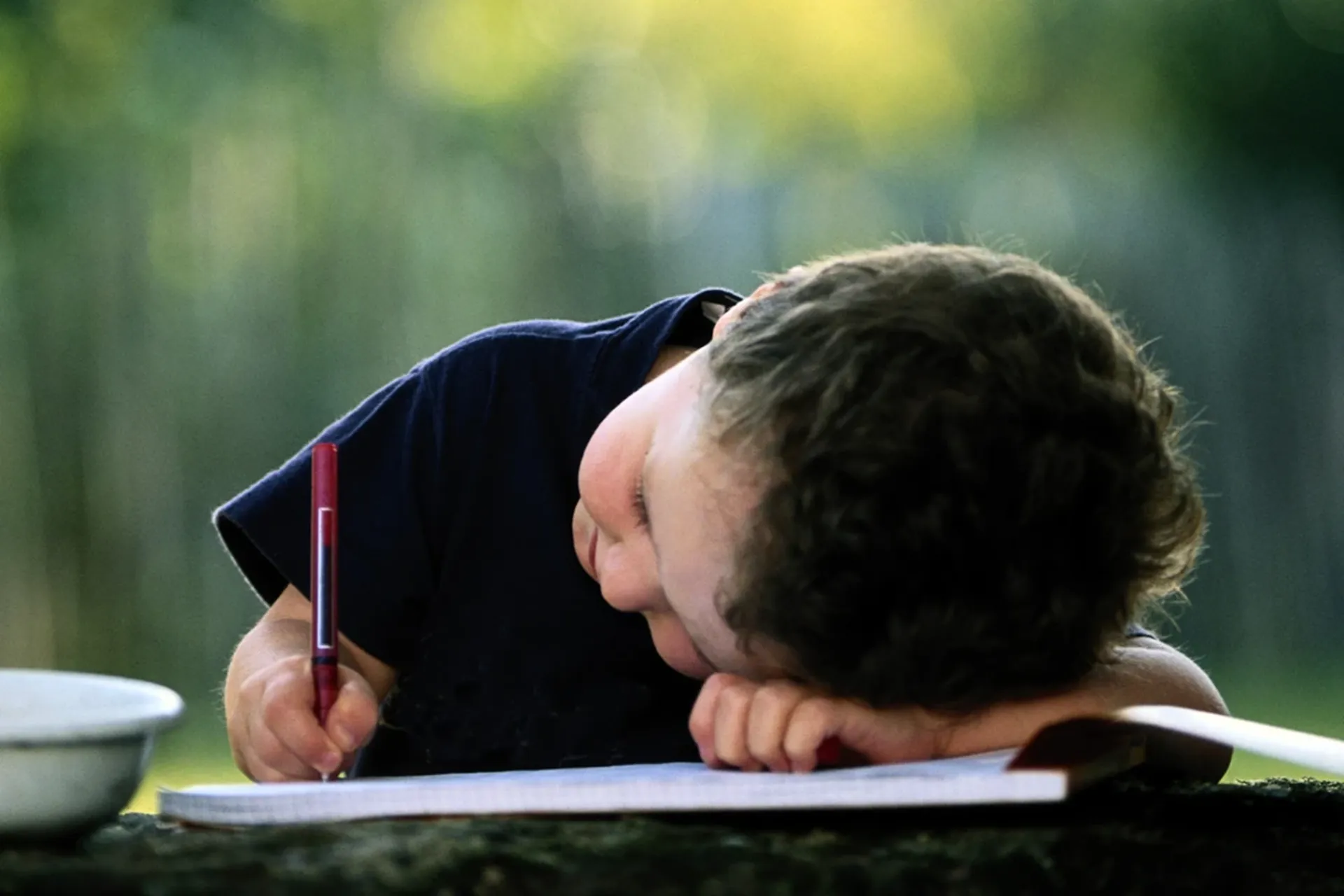 Boy bent over writing in a notebook