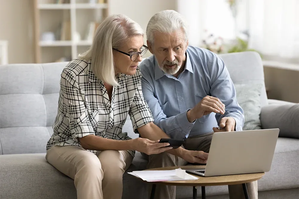 Older couple discussing something they see on a laptop
