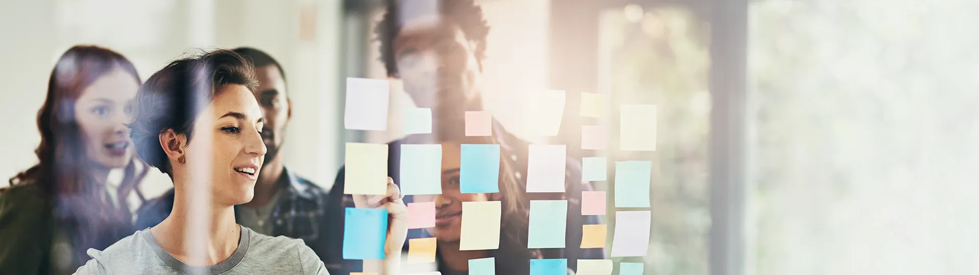 Team writing on sticky notes, stuck to glass wall