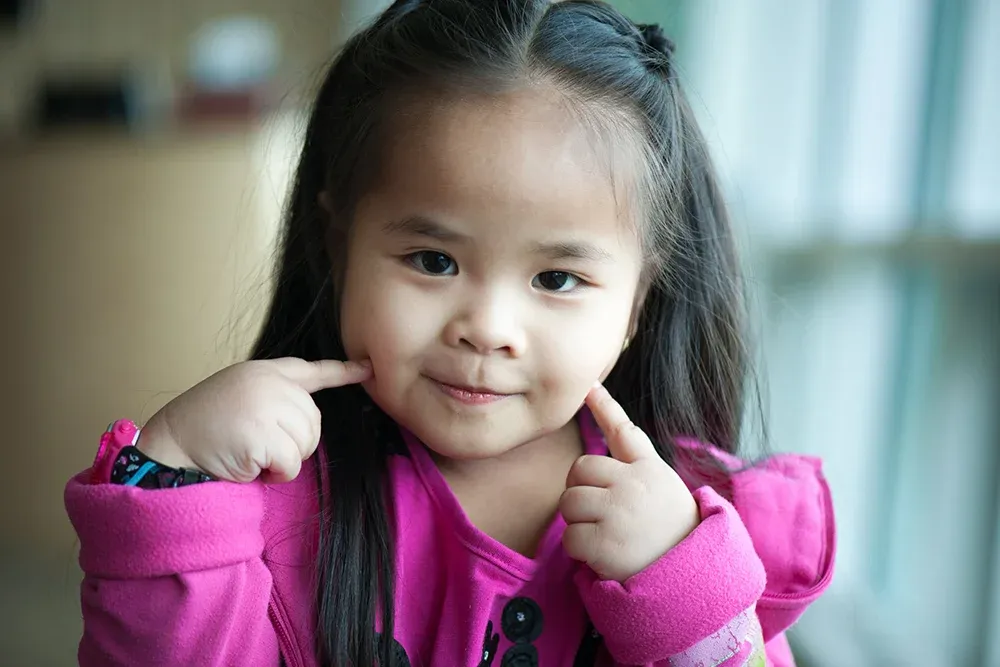 Young girl poking her own cheeks with her index fingers