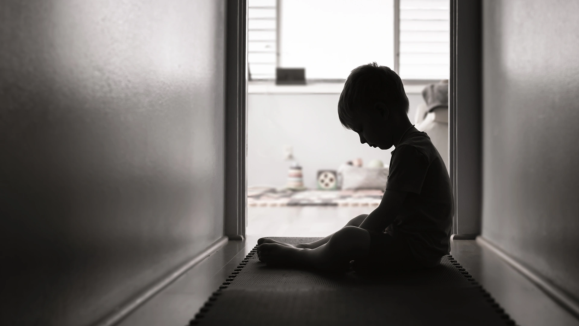 Silhouette of a boy sitting in a hallway, dejected