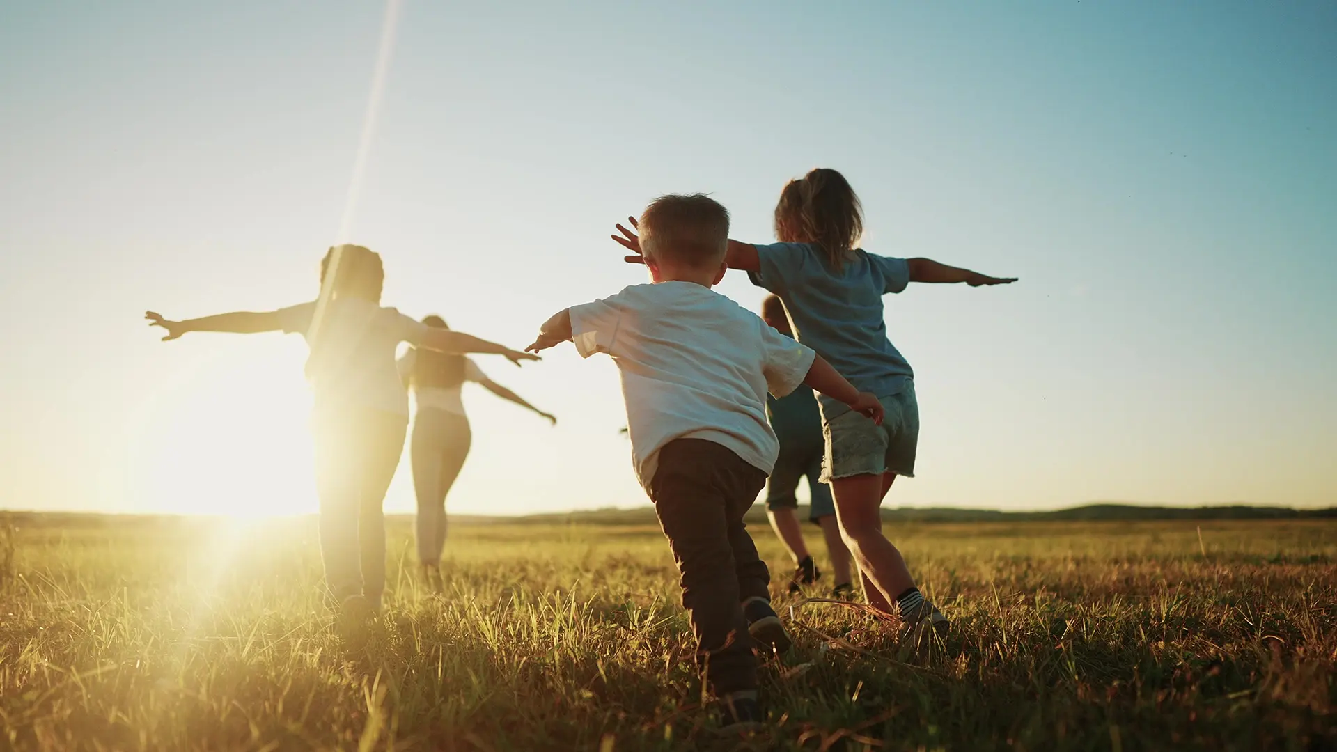 Kids running in the park at sunset