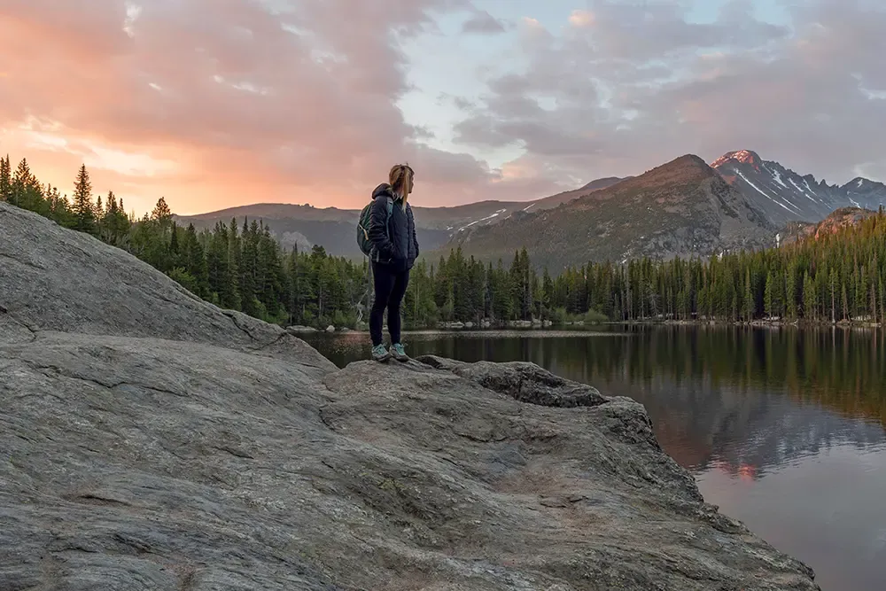 Hiker at alpine lake during sunset