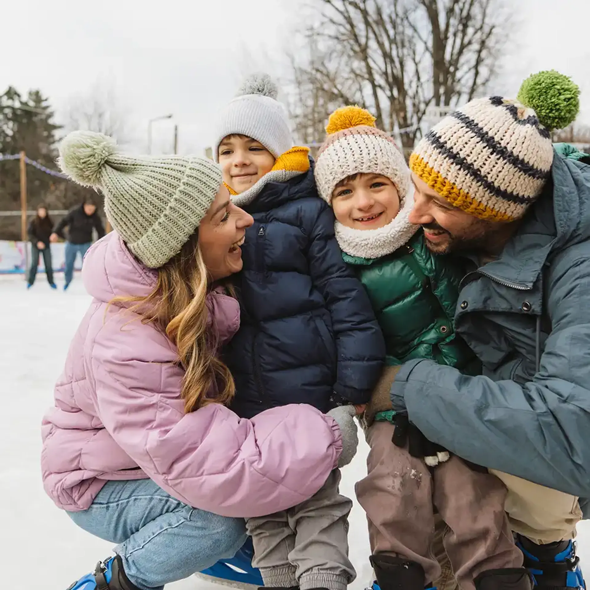 Parents hugging smiling kids while ice skating