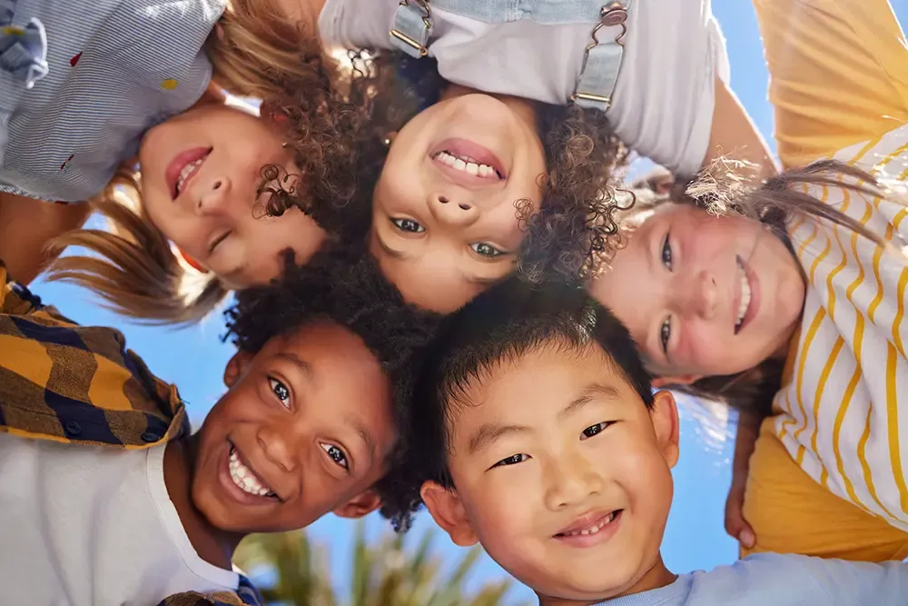 Five children, their heads together, smiling down at the camera