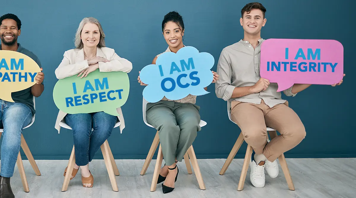 Four people holding signs saying: I am empathy, I am respect, I am OCS, and I am integrity.