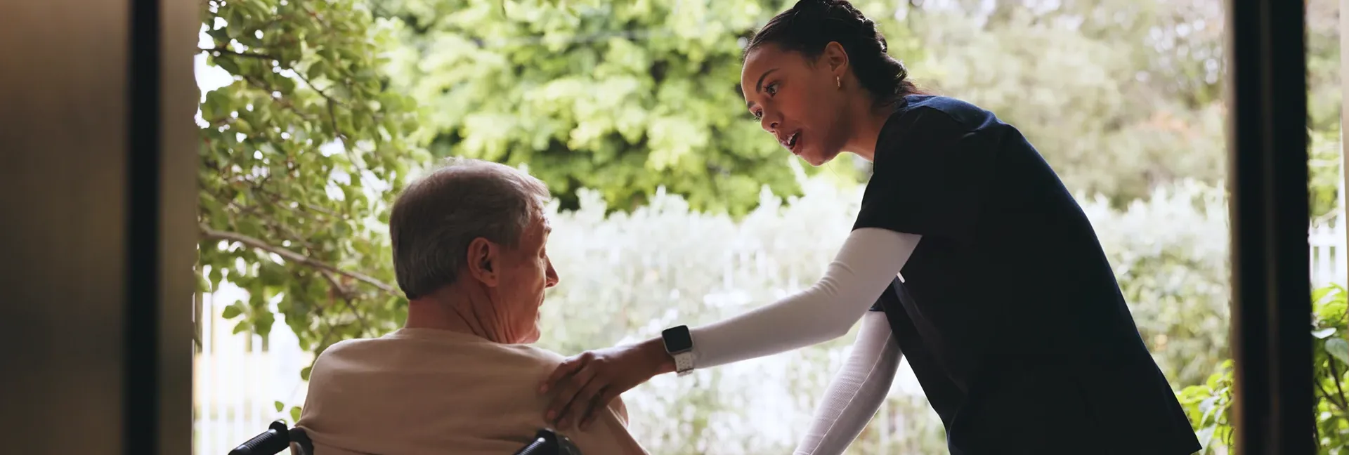 Caregiver speaking with elder in wheelchair