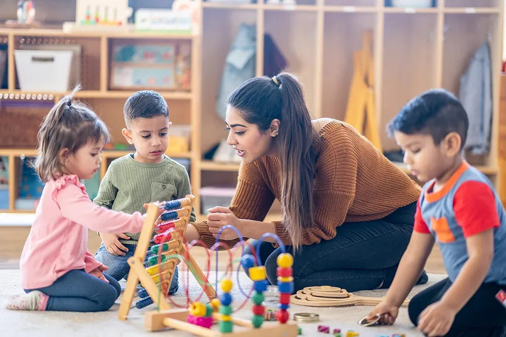 Woman playing with 3 children on the floor