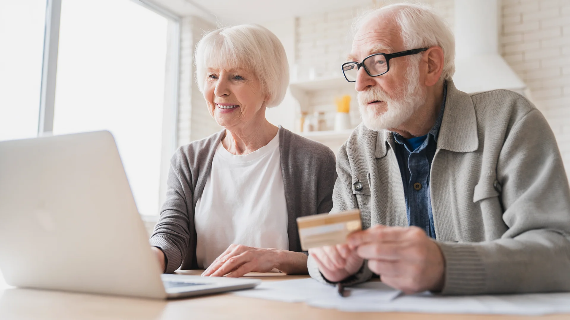 Older couple looking at laptop with credit card ready