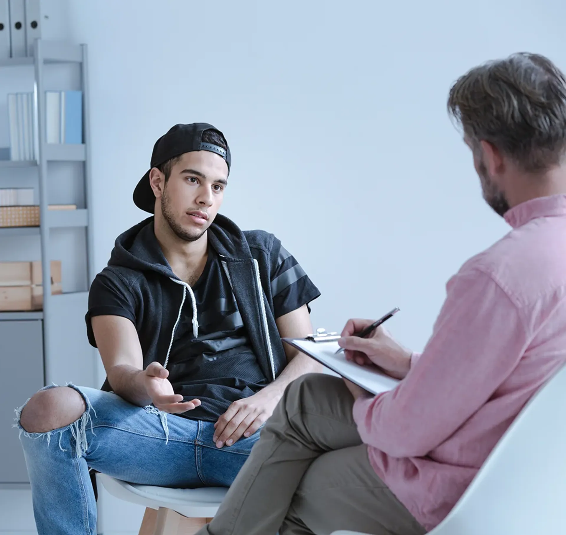 Troubled teenage speaking with an adult who is taking notes
