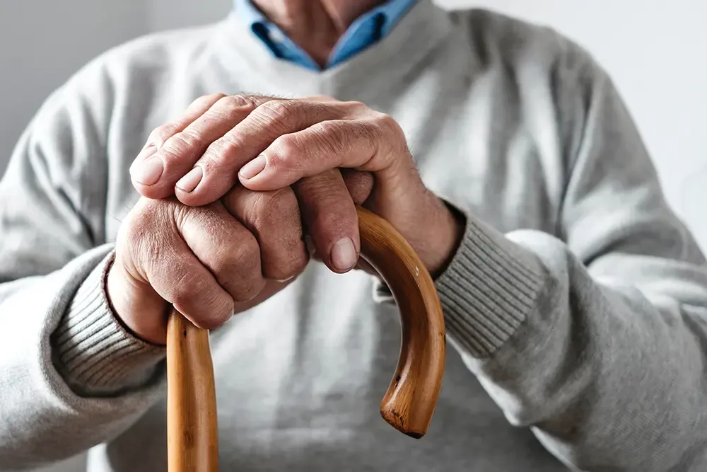 Closeup on and elderly man's hands, resting on a cane