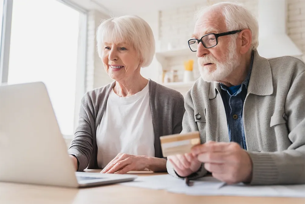 Older couple looking at laptop with credit card ready
